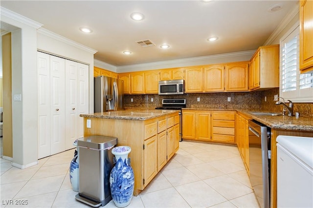 kitchen featuring appliances with stainless steel finishes, a kitchen island, crown molding, and sink