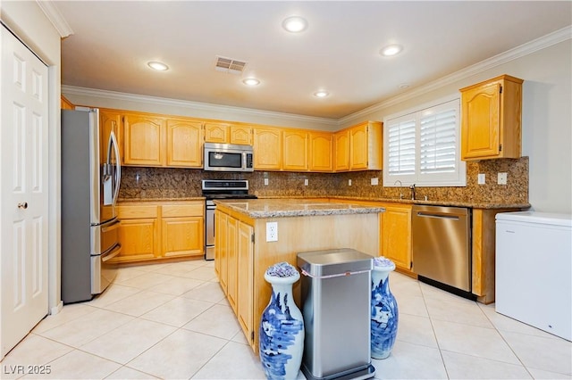 kitchen featuring light stone counters, stainless steel appliances, crown molding, light tile patterned floors, and a center island