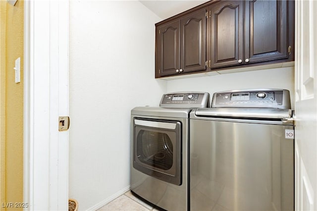 laundry room with washing machine and dryer, light tile patterned floors, and cabinets