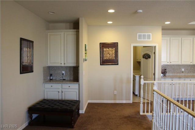 kitchen featuring white cabinets, decorative backsplash, and dark carpet