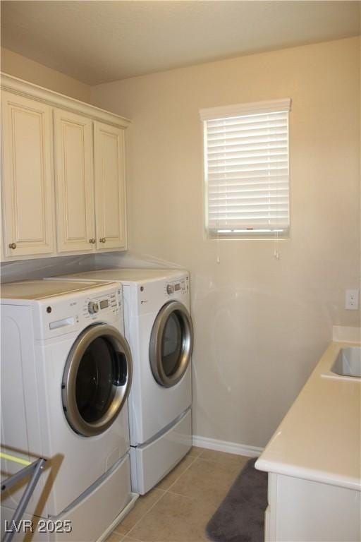 laundry room featuring washer and dryer, cabinets, and light tile patterned flooring