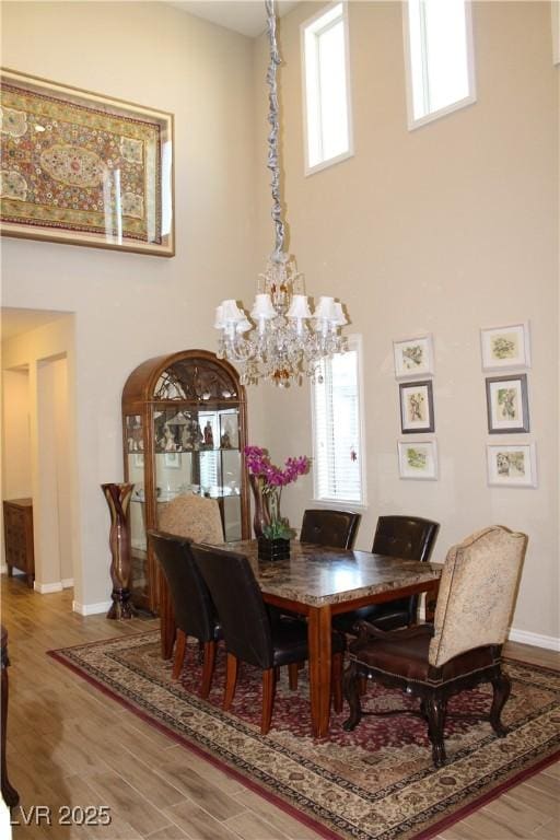 dining area featuring a chandelier, a high ceiling, and hardwood / wood-style flooring