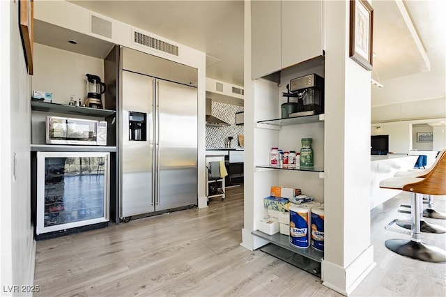 kitchen featuring stainless steel appliances, wine cooler, and light hardwood / wood-style flooring