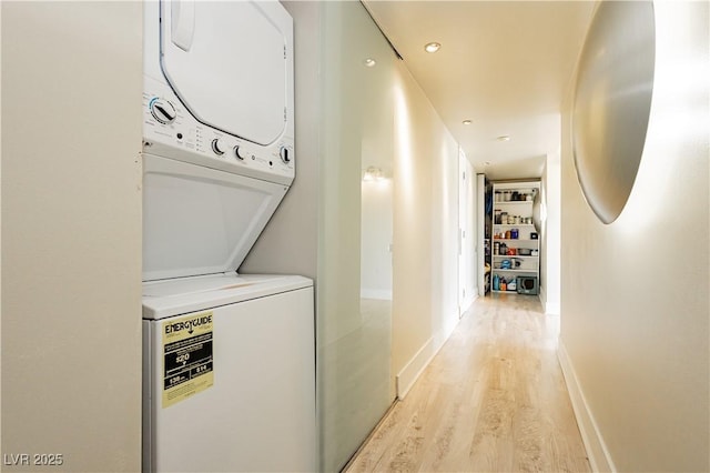 washroom with stacked washer / drying machine and light wood-type flooring