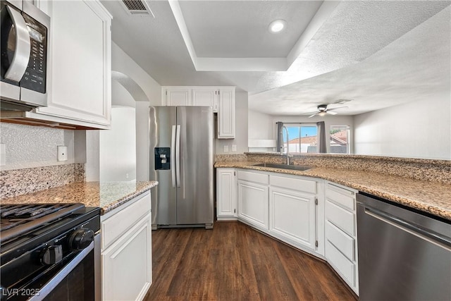 3320 Haven Beach Way, Las Vegas, NV 89117 - kitchen with stainless steel appliances, a ceiling fan, dark wood finished floors, white cabinetry, and a tray ceiling