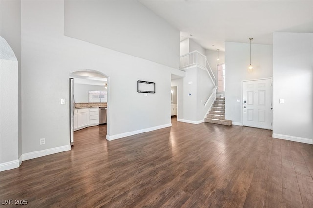 3320 Haven Beach Way, Las Vegas, NV 89117 - unfurnished living room featuring arched walkways, high vaulted ceiling, dark wood finished floors, and stairs