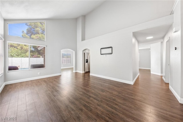 3320 Haven Beach Way, Las Vegas, NV 89117 - unfurnished living room featuring arched walkways, dark wood finished floors, and a towering ceiling