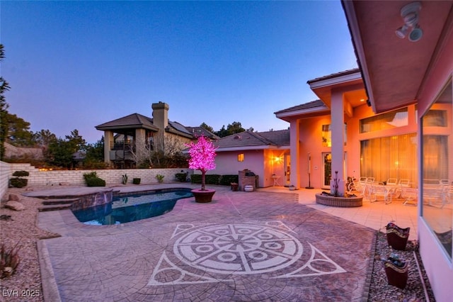 pool at dusk with a patio area