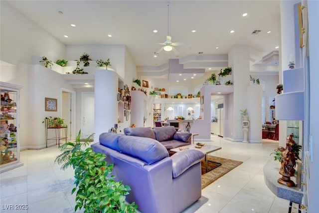 living room with a towering ceiling, ceiling fan, and light tile patterned flooring