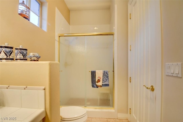 bathroom featuring tile patterned flooring, a shower with shower door, and toilet