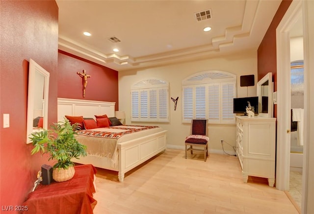 bedroom featuring a raised ceiling and light wood-type flooring