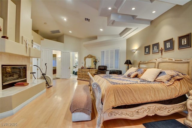 bedroom featuring a fireplace, a high ceiling, and light hardwood / wood-style floors