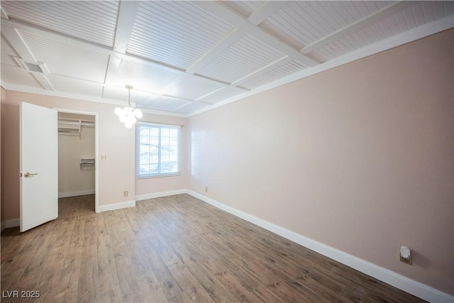 unfurnished bedroom featuring hardwood / wood-style flooring, an inviting chandelier, and a closet