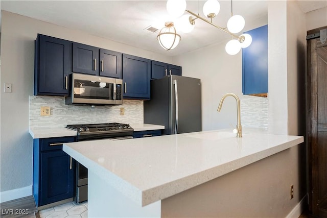 kitchen featuring sink, stainless steel appliances, blue cabinets, decorative light fixtures, and decorative backsplash