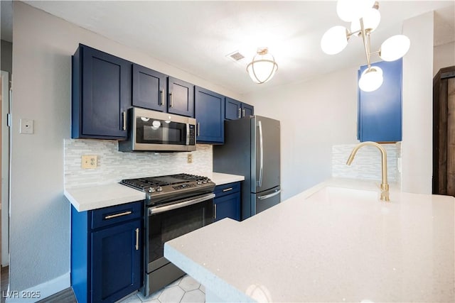 kitchen with blue cabinetry, backsplash, sink, and stainless steel appliances