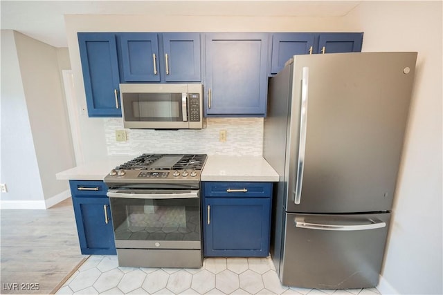 kitchen featuring blue cabinets, backsplash, and appliances with stainless steel finishes