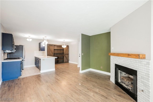 kitchen with tasteful backsplash, light wood-type flooring, sink, and a brick fireplace