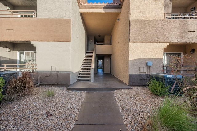 view of exterior entry featuring a balcony and central AC unit