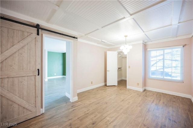 unfurnished room featuring a barn door, a chandelier, and wood-type flooring