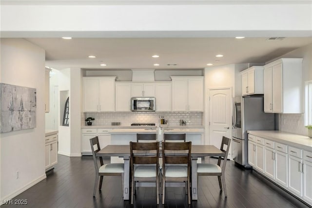 kitchen with white cabinets, decorative backsplash, dark hardwood / wood-style flooring, and stainless steel appliances