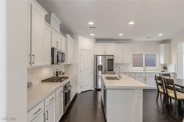 kitchen featuring white cabinets, decorative backsplash, stainless steel appliances, and sink