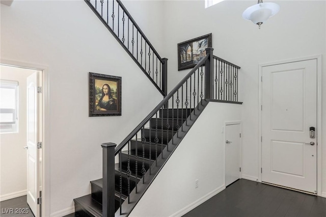 stairway featuring hardwood / wood-style floors and a towering ceiling