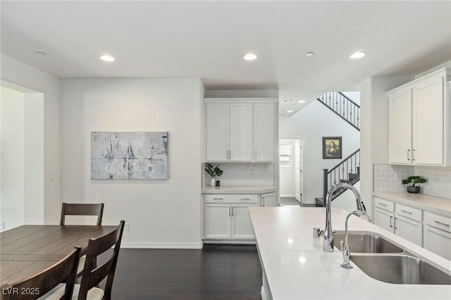 kitchen with backsplash, white cabinetry, and sink