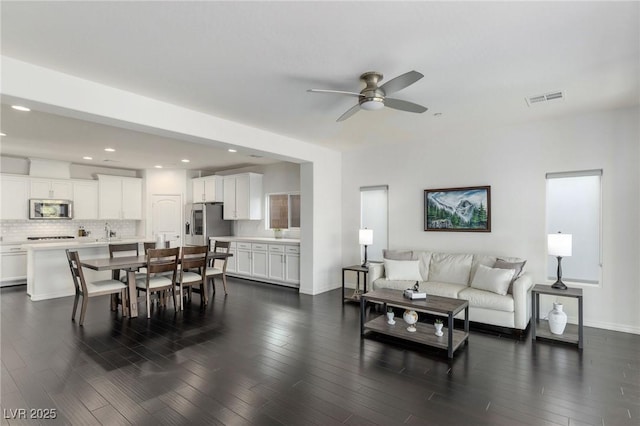 living room with dark hardwood / wood-style floors, ceiling fan, and sink