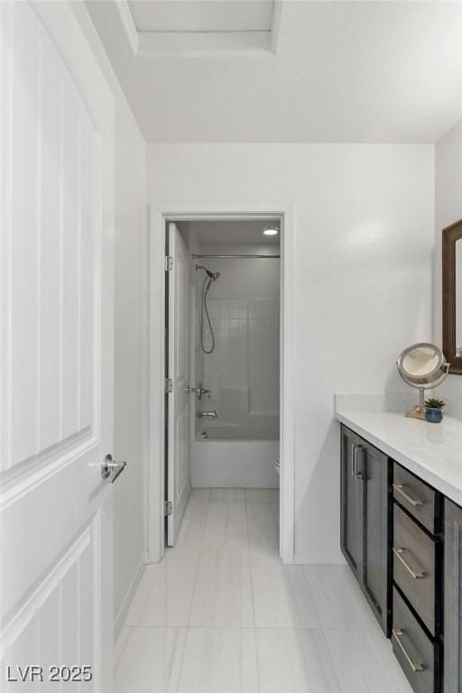 bathroom with tile patterned floors, vanity, a raised ceiling, and tiled shower / bath