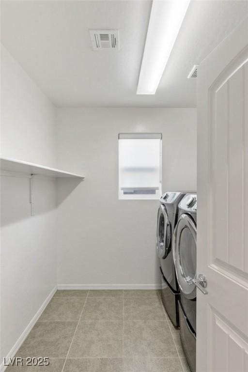 clothes washing area with light tile patterned floors and washer and clothes dryer