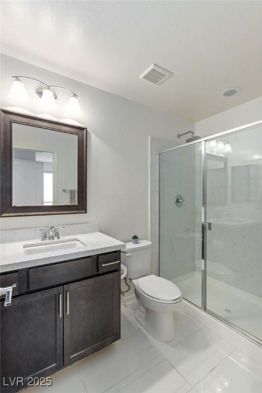 bathroom with tile patterned floors, vanity, toilet, and walk in shower