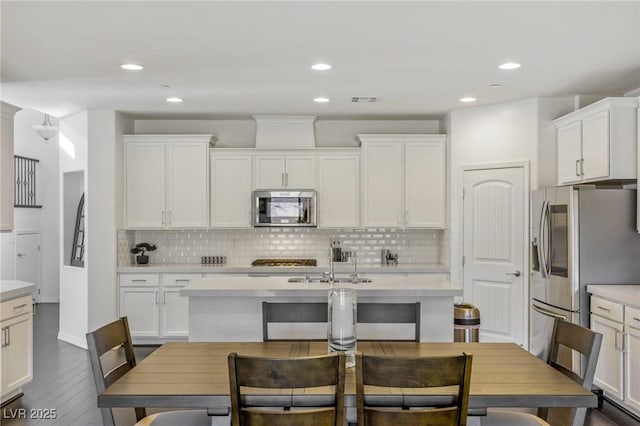 kitchen with white cabinetry, sink, stainless steel appliances, dark hardwood / wood-style flooring, and decorative backsplash