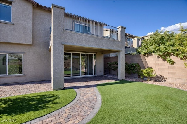 rear view of property with a balcony, a yard, and a patio