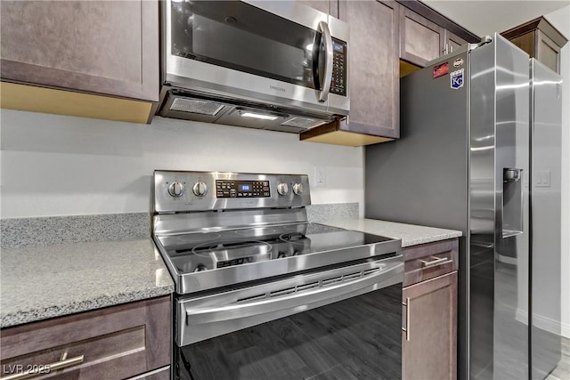 kitchen with dark brown cabinets, stainless steel appliances, and light stone counters