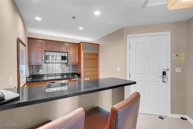 kitchen with backsplash, light tile patterned flooring, and stainless steel appliances