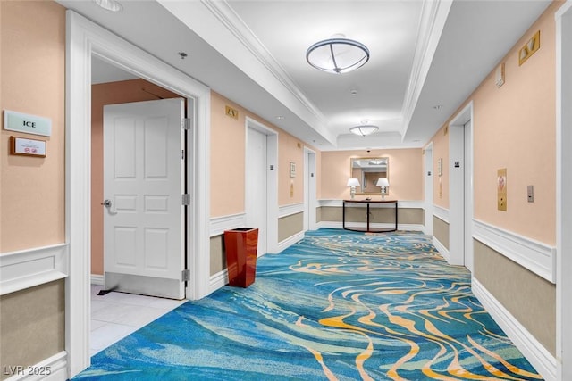 corridor featuring a tray ceiling, elevator, and ornamental molding