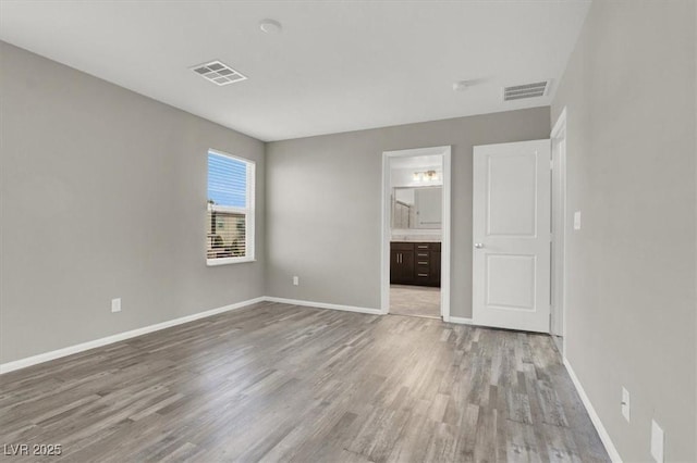 unfurnished bedroom with baseboards, visible vents, and wood finished floors