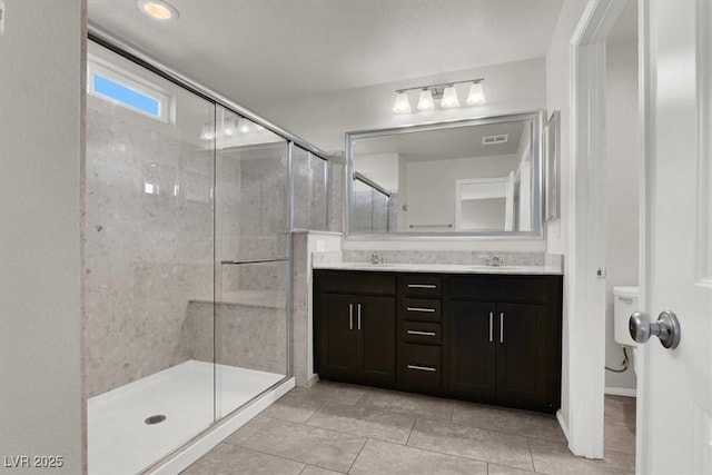 full bathroom featuring a sink, visible vents, a shower stall, tile patterned floors, and double vanity