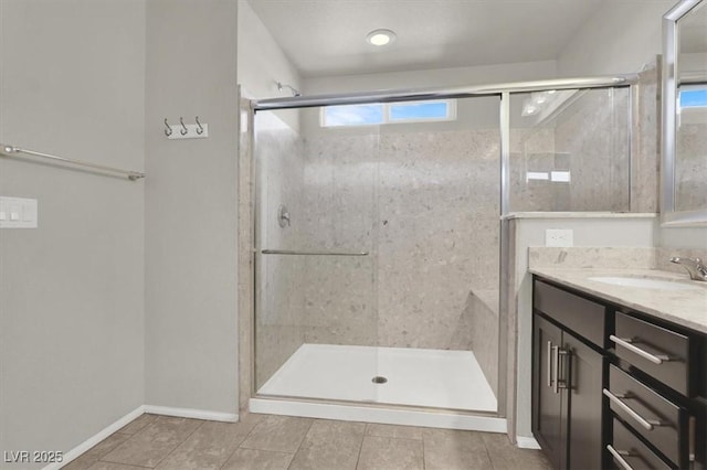 full bathroom featuring a stall shower, tile patterned flooring, vanity, and baseboards