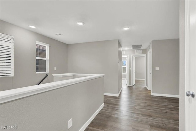 corridor featuring dark wood-style flooring, recessed lighting, visible vents, an upstairs landing, and baseboards