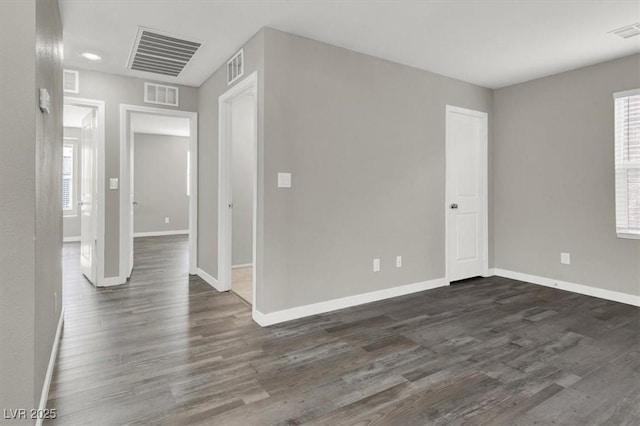 unfurnished room with baseboards, visible vents, and dark wood finished floors