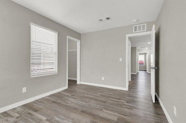 spare room with baseboards, visible vents, and wood finished floors