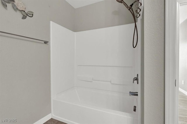 full bathroom featuring bathtub / shower combination and baseboards