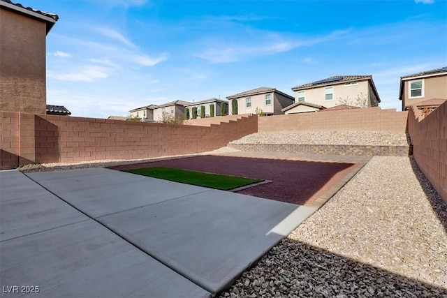 view of yard featuring a residential view, a patio area, and a fenced backyard