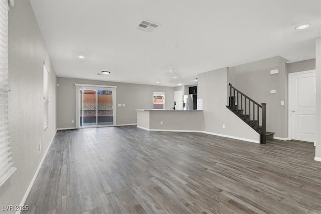 unfurnished living room featuring recessed lighting, visible vents, baseboards, stairway, and dark wood-style floors