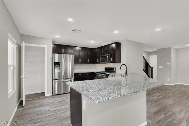 kitchen with light wood finished floors, visible vents, appliances with stainless steel finishes, a sink, and light stone countertops