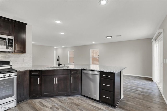 kitchen featuring light wood-type flooring, appliances with stainless steel finishes, decorative backsplash, and a sink