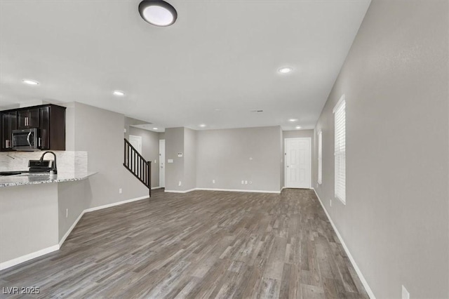 unfurnished living room with stairway, wood finished floors, and baseboards