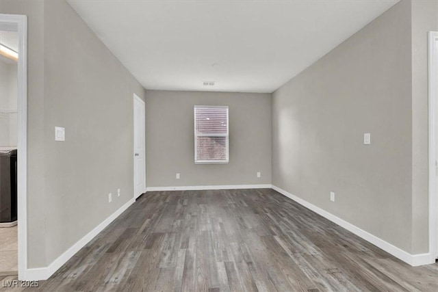 spare room featuring wood finished floors, visible vents, and baseboards