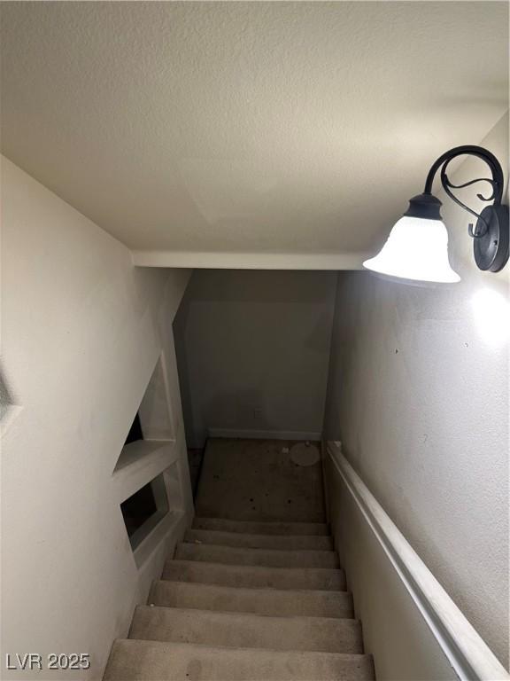 staircase featuring a textured ceiling